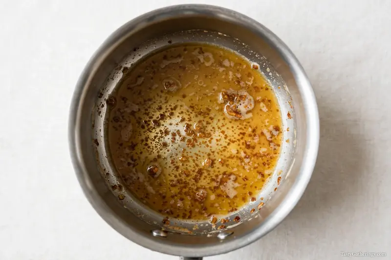 Golden brown butter in stainless steel saucepan showing toasted milk solids, top-down shot.