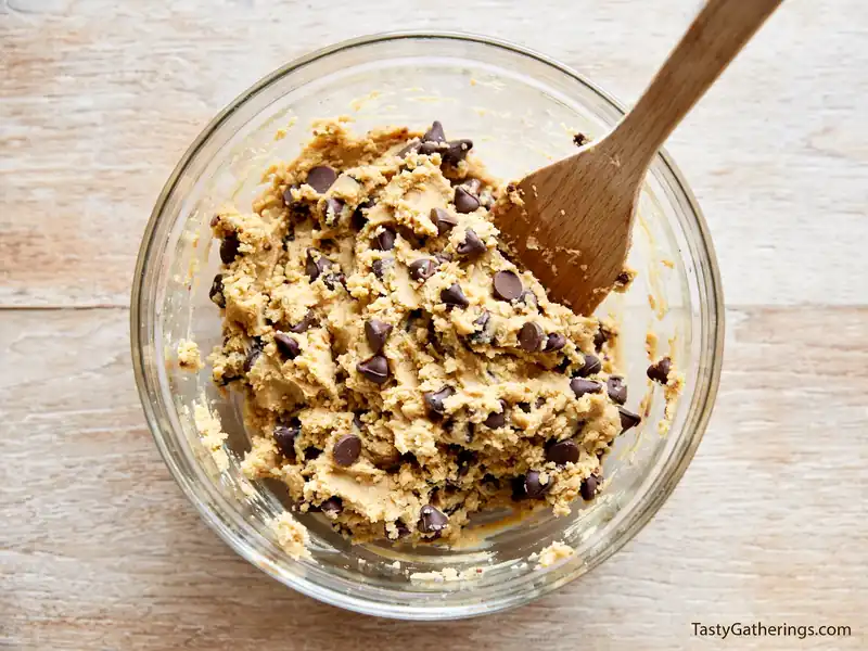 Peanut Butter Chocolate Chip Cookies dough mixed with chocolate chips in glass bowl with spatula.
